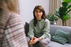 A focused woman during a therapy session at the best treatment facility outpatient program in va, seated on a sofa indoors.