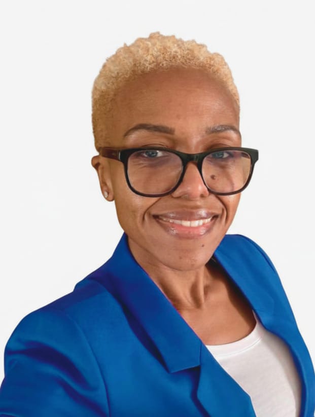 0c6994eb-af46-49cb-a13c-7ab41d2d7be1 A person with short blond hair, wearing black glasses, a blue blazer, and a white shirt, smiling at the camera against a plain white background, portraying the approachable and professional demeanor of an addiction professional Roanoke trusts.